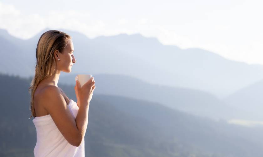 Frau hält Tasse in der Hand mit Blick auf das Dachsteingebirge