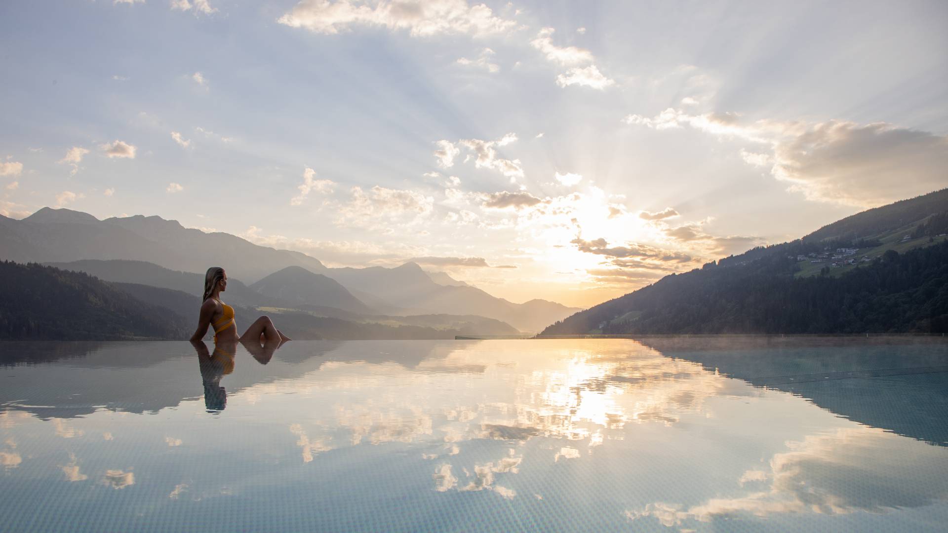 Frau sitzt am Infinitypool im 4* Hotel Schütterhof in Schladming